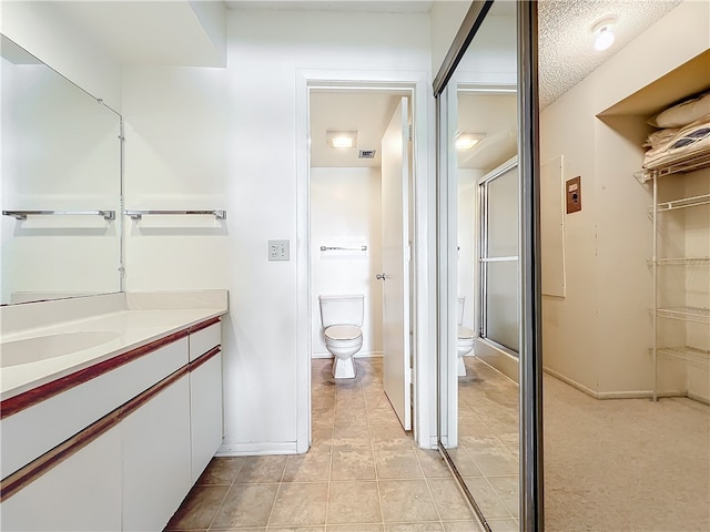 bathroom featuring tile patterned floors, toilet, a textured ceiling, an enclosed shower, and vanity