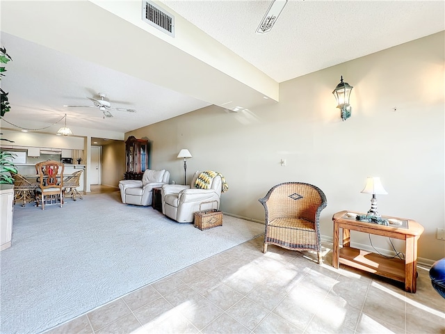 living area featuring a textured ceiling, light carpet, and ceiling fan