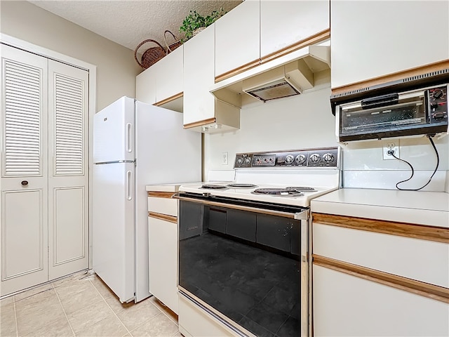 kitchen with white appliances, white cabinetry, light tile patterned floors, and a textured ceiling