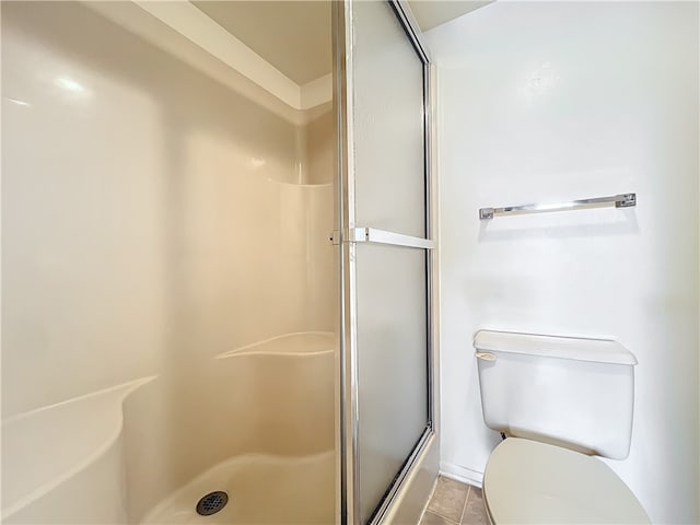 bathroom with toilet, an enclosed shower, and tile patterned flooring