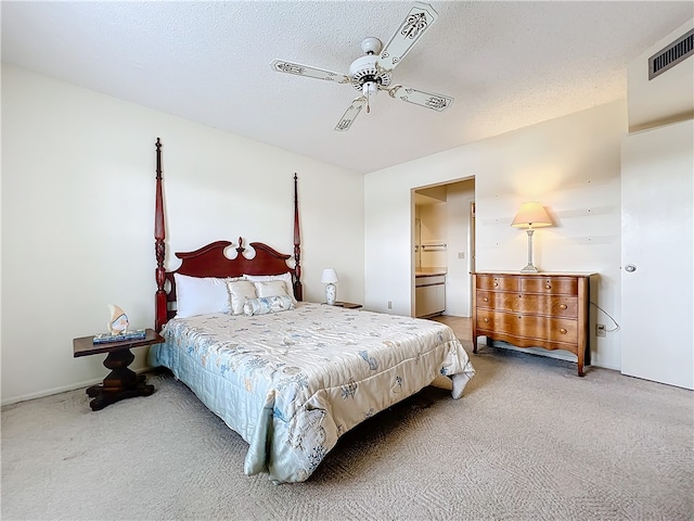 carpeted bedroom featuring ceiling fan, ensuite bath, and a textured ceiling