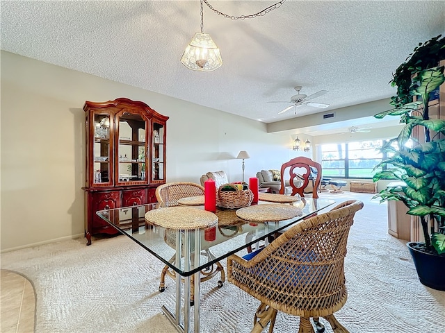 carpeted dining room with ceiling fan and a textured ceiling