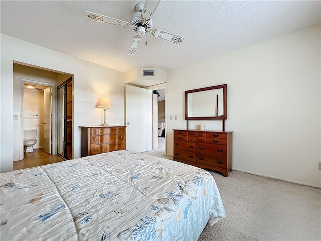 carpeted bedroom featuring a textured ceiling, ensuite bath, and ceiling fan