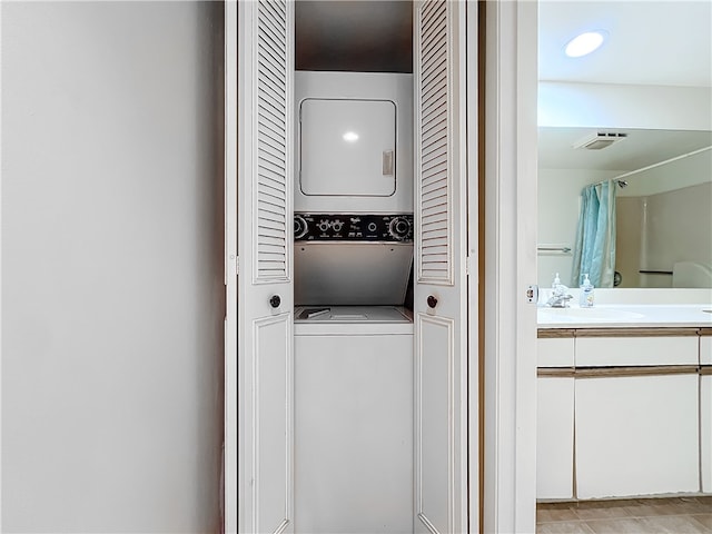 laundry area with stacked washer and dryer, sink, and light tile patterned floors