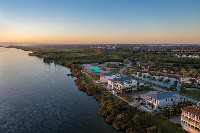 aerial view at dusk featuring a water view