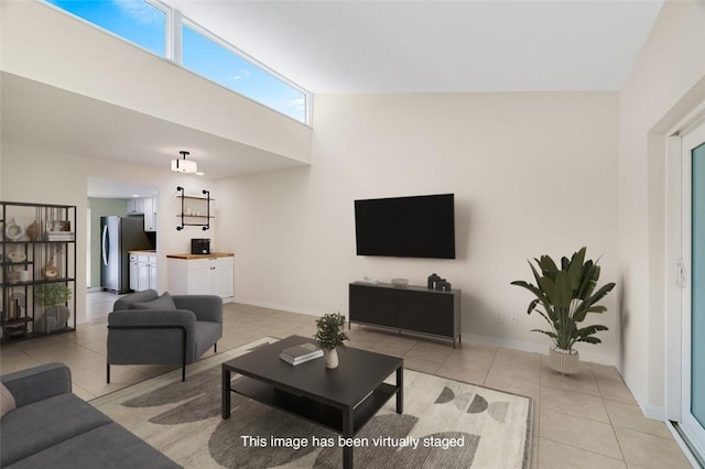 living area with light tile patterned floors, a towering ceiling, and baseboards