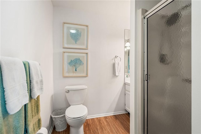 bathroom with hardwood / wood-style flooring, vanity, a shower with door, and toilet