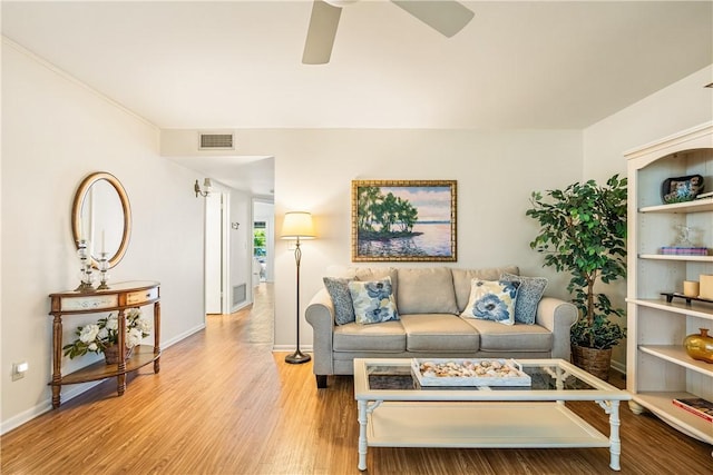 living room with a ceiling fan, light wood-type flooring, visible vents, and baseboards