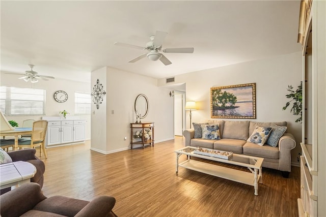 living area with visible vents, baseboards, a ceiling fan, and wood finished floors