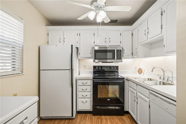 kitchen with white appliances, light wood-type flooring, white cabinets, ceiling fan, and sink