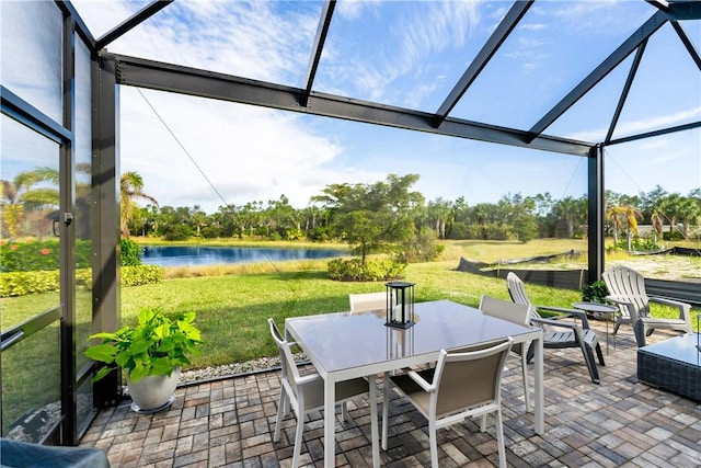 view of patio with glass enclosure and a water view