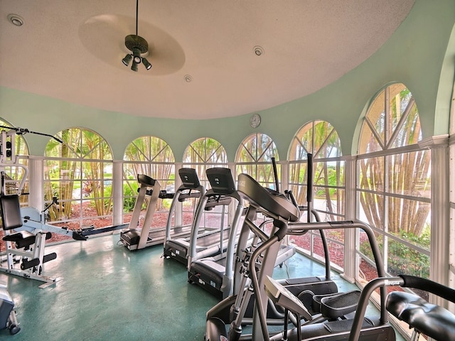 exercise room featuring ceiling fan, a textured ceiling, and a healthy amount of sunlight