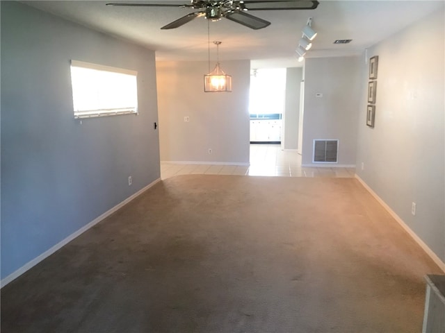 empty room featuring ceiling fan, light colored carpet, a healthy amount of sunlight, and track lighting