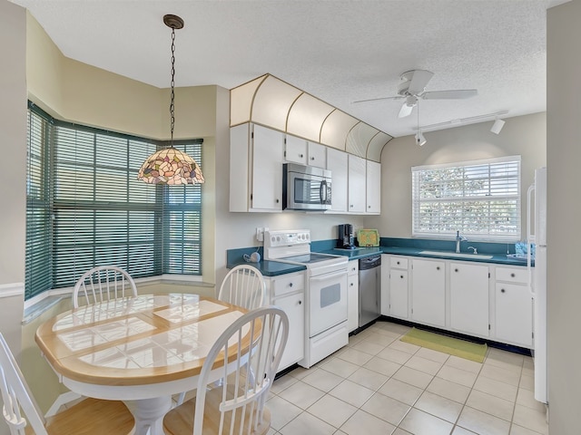 kitchen featuring stainless steel appliances, decorative light fixtures, a textured ceiling, sink, and white cabinets