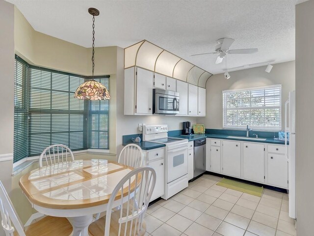 482 Grove Isle Cir Unit 482, Vero Beach, FL 32962 - kitchen with appliances with stainless steel finishes, a sink, dark countertops, white cabinetry, and ceiling fan