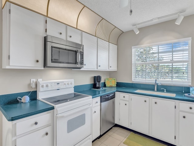 kitchen featuring sink, appliances with stainless steel finishes, rail lighting, a textured ceiling, and white cabinets