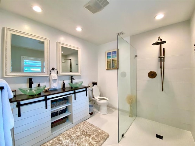 bathroom featuring vanity, a tile shower, tile patterned floors, and toilet