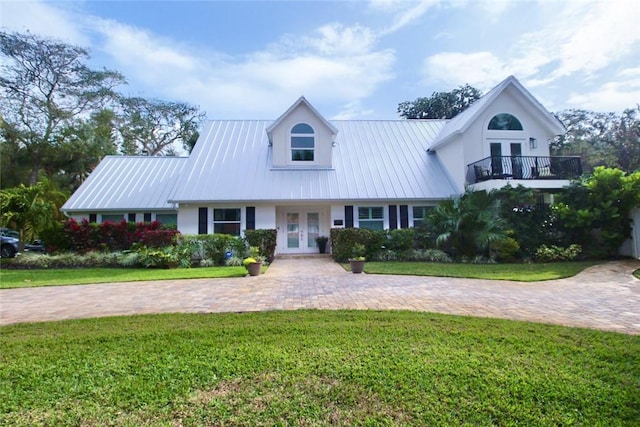 view of front of home featuring a balcony, a front lawn, and french doors