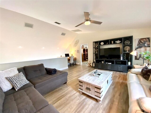 living room featuring ceiling fan, vaulted ceiling, and light wood-type flooring