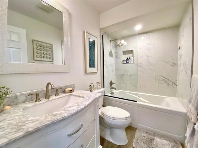 full bathroom with tiled shower / bath combo, vanity, hardwood / wood-style floors, and toilet