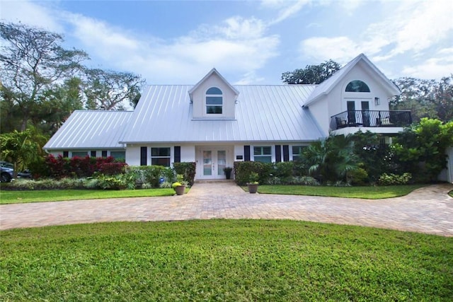 view of front facade with a front lawn, french doors, and a balcony