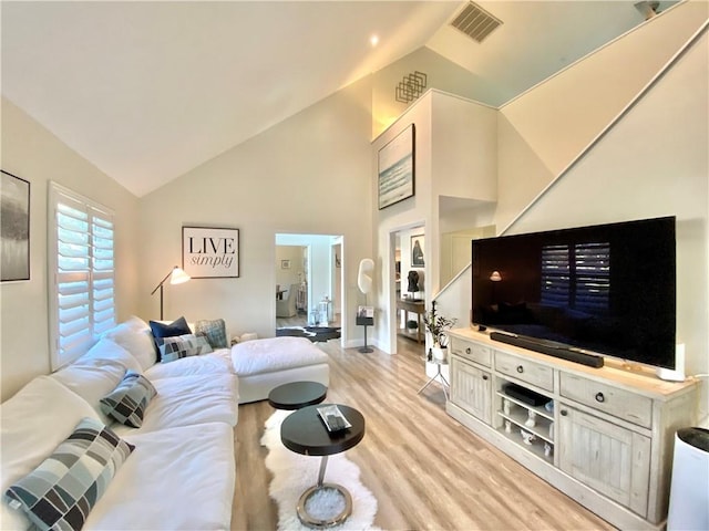 living room with high vaulted ceiling and light hardwood / wood-style flooring