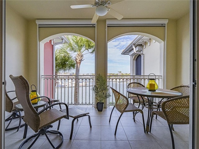 sunroom with a water view and ceiling fan