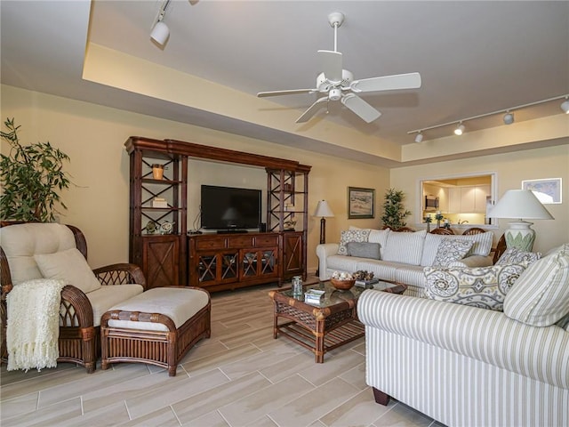 living room featuring a raised ceiling, ceiling fan, and track lighting