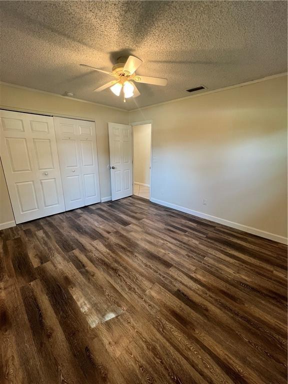 unfurnished bedroom with dark wood-style flooring, baseboards, a closet, and a textured ceiling