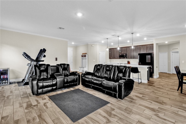 living room featuring crown molding, beverage cooler, a textured ceiling, and light wood-type flooring