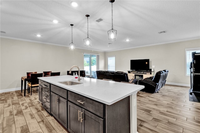 kitchen with sink, dark brown cabinets, hanging light fixtures, a center island with sink, and black dishwasher