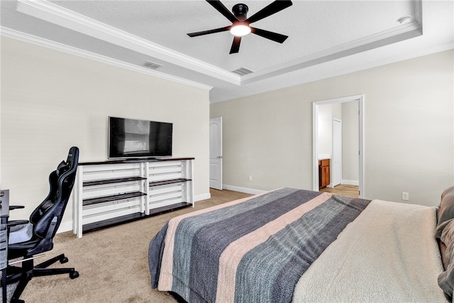 bedroom featuring light colored carpet, a textured ceiling, ornamental molding, a tray ceiling, and ceiling fan