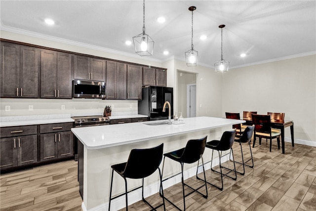 kitchen featuring stainless steel appliances, an island with sink, hanging light fixtures, and sink