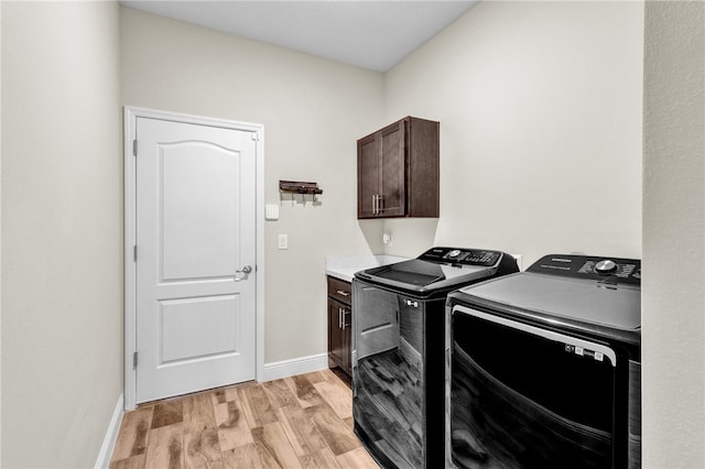 laundry area with cabinets, washing machine and dryer, and light wood-type flooring