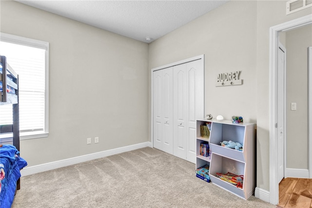 bedroom with light carpet, a closet, and a textured ceiling