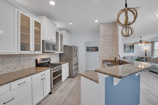 kitchen featuring tasteful backsplash, open floor plan, appliances with stainless steel finishes, a kitchen breakfast bar, and a sink