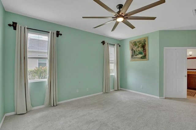 spare room with visible vents, baseboards, light colored carpet, and a ceiling fan