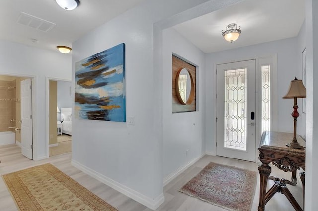 entryway with light wood-style floors, baseboards, and visible vents