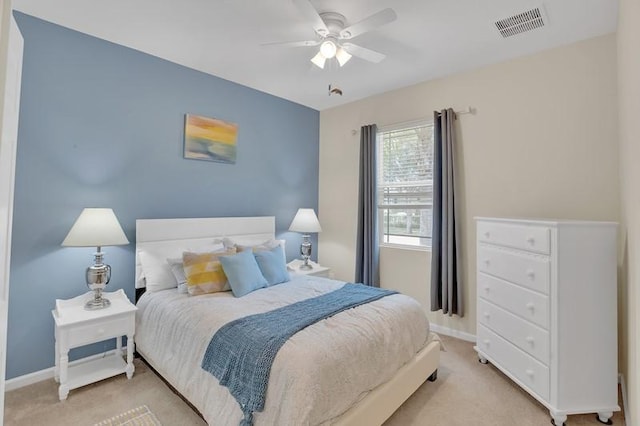 bedroom with visible vents, light colored carpet, baseboards, and ceiling fan