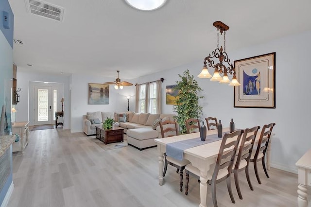 dining space featuring light wood finished floors, visible vents, and baseboards