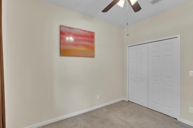 unfurnished bedroom with a closet, baseboards, carpet, and ceiling fan