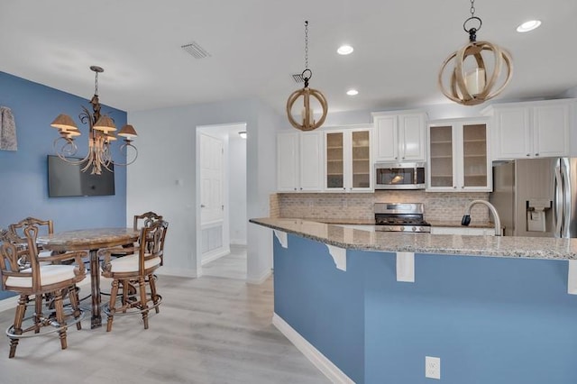 kitchen featuring tasteful backsplash, a notable chandelier, appliances with stainless steel finishes, and light stone countertops