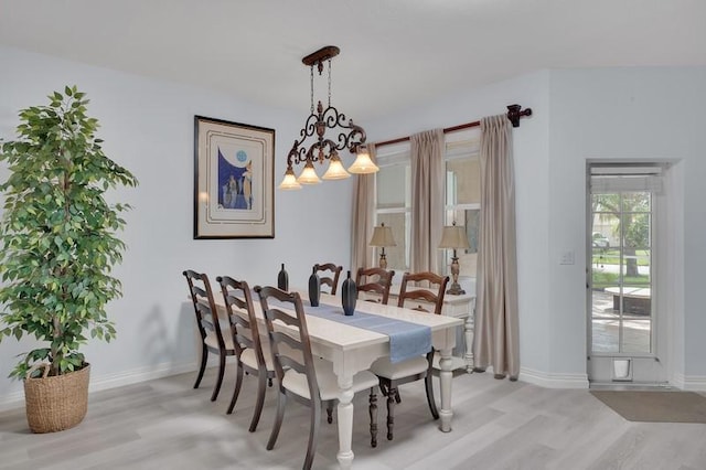 dining area with light wood-type flooring, baseboards, and a chandelier