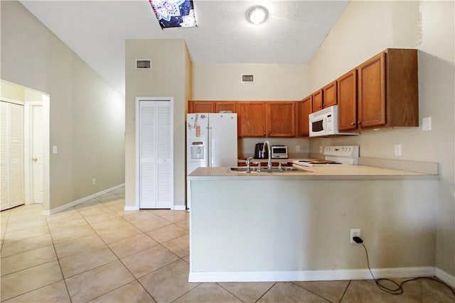 kitchen featuring a high ceiling, white appliances, light tile patterned flooring, sink, and kitchen peninsula