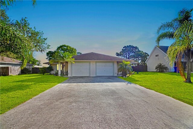 ranch-style house featuring a garage and a lawn