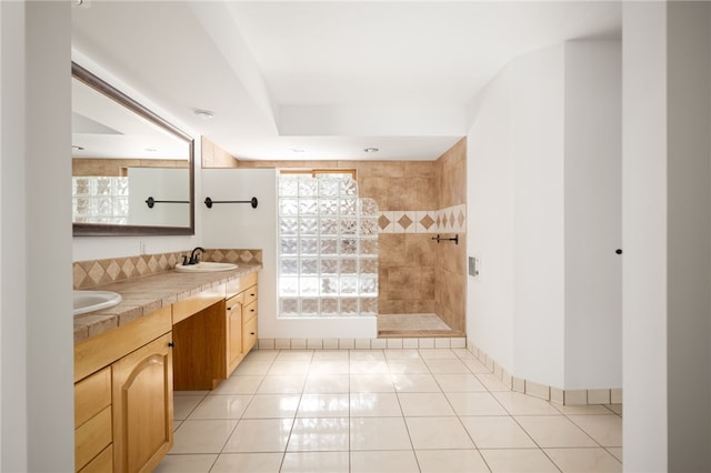 bathroom with tile patterned floors, vanity, and a tile shower