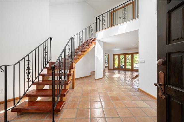 stairs featuring tile patterned flooring and high vaulted ceiling