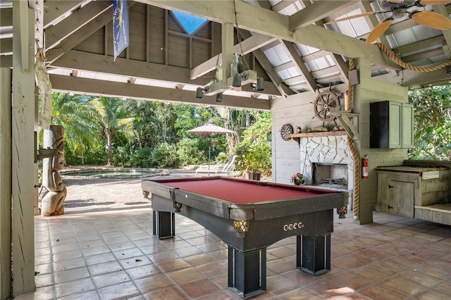 game room with lofted ceiling with beams, ceiling fan, an outdoor stone fireplace, and pool table