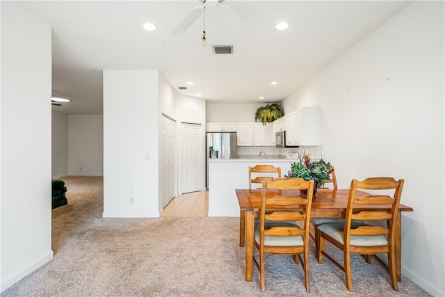 dining room with ceiling fan and light colored carpet