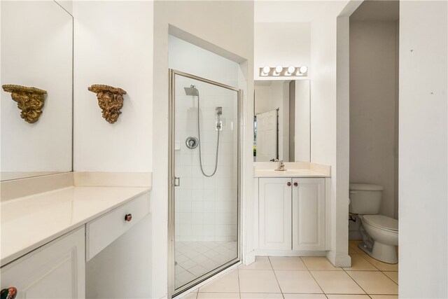 bathroom featuring tile patterned floors, toilet, vanity, and walk in shower